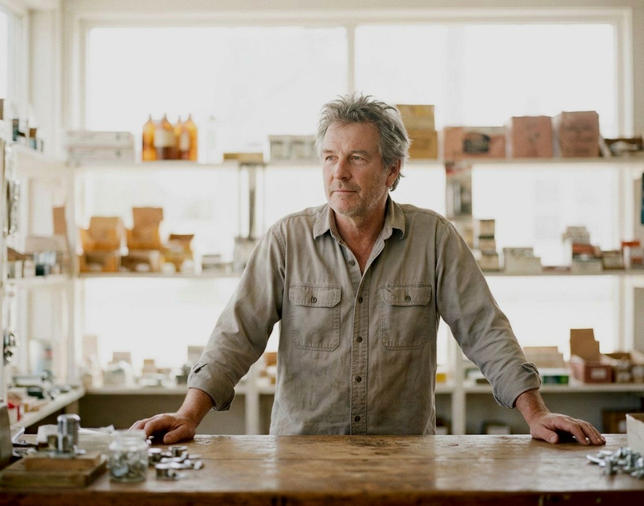 A shop owner standing behind the counter of his own hardware store.